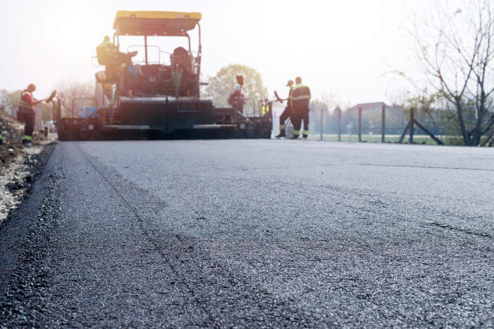 workers placing new coating asphalt road